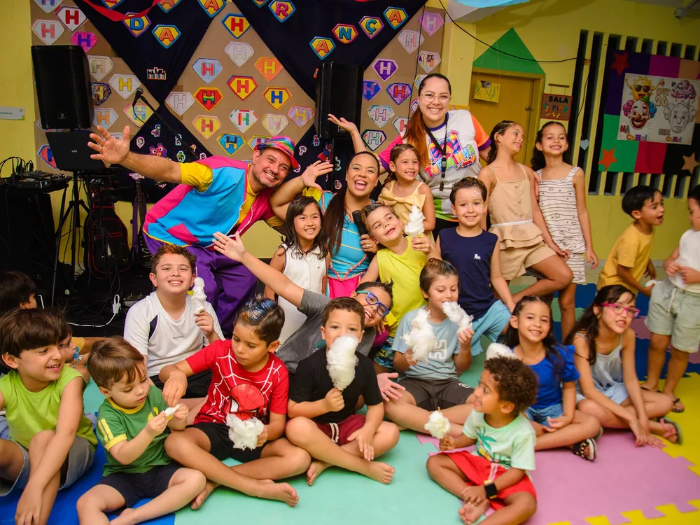 Estudantes sentados em roda no chão da sala, ouvindo uma história durante a Festa do Pijama