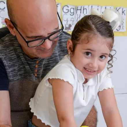 Pai e filha sorrindo juntos em uma sala de aula da escola